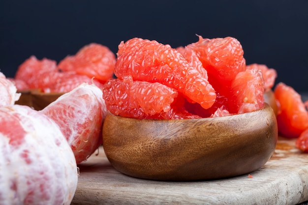 Очищенный розовый грейпфрут, разрезанный на кусочки во время приготовления, готов к употреблению сочный цитрусовый грейпфрут