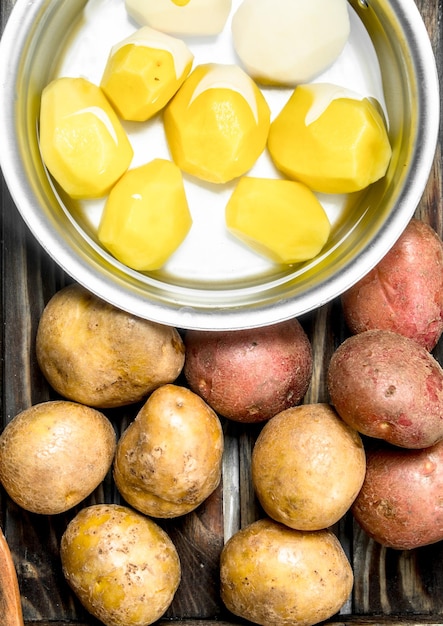 Peeled potatoes in a pot and fresh potatoes