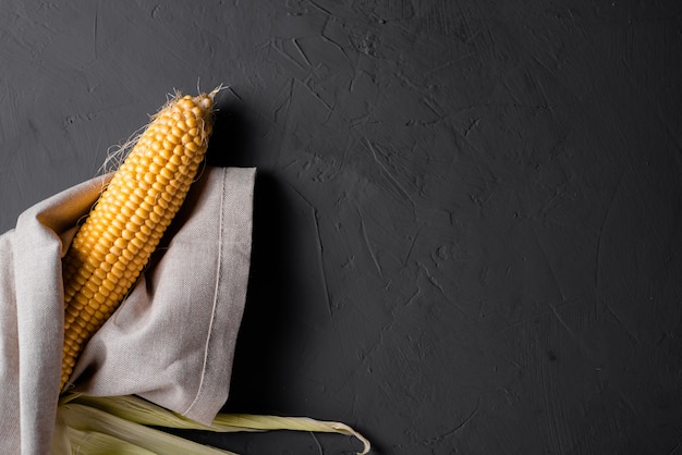 Peeled raw corn on a gray concrete background.