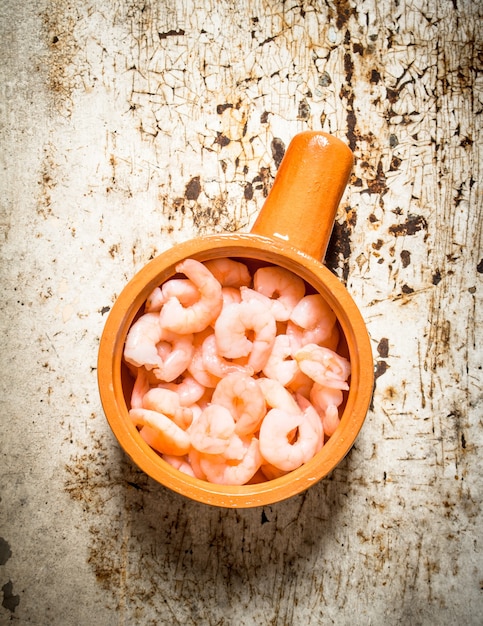 Peeled shrimp in a bowl on rustic .