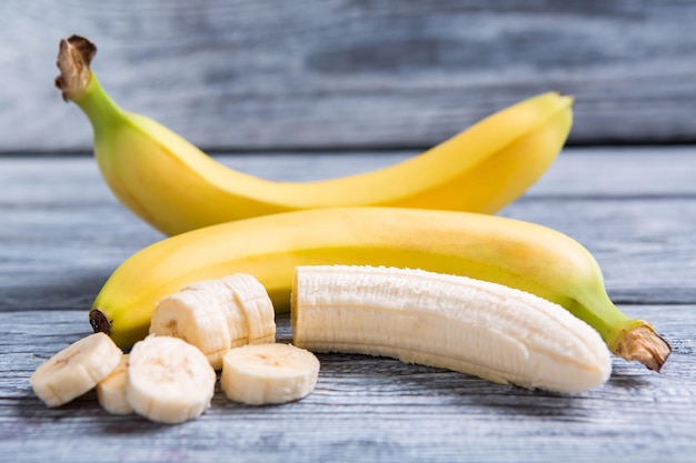 Peeled and sliced banana bananas on gray wooden backround sweet food high in calories fruit of tropics