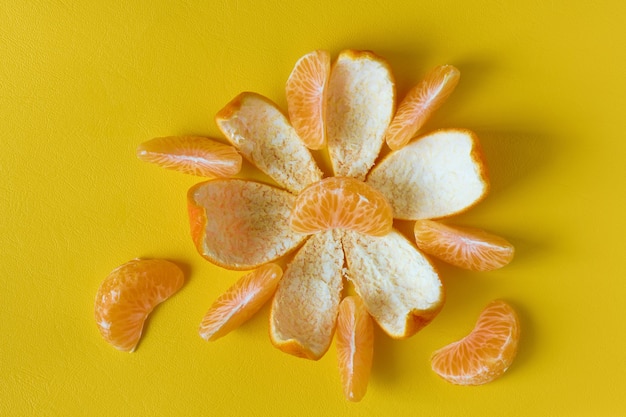 Photo peeled tangerine or mandarin fruit on yellow surface, flat lay