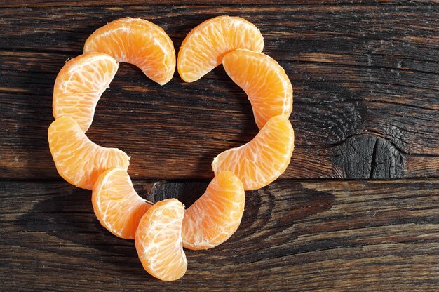 Foto mandarino sbucciato a forma di cuore su tavola in legno rustico