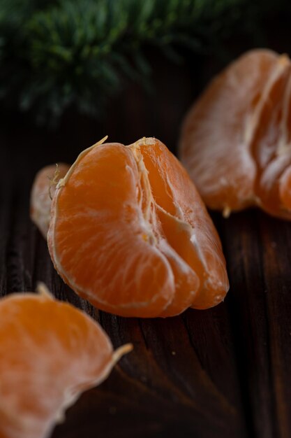 A peeled tangerine on a wooden table among spruce twigs