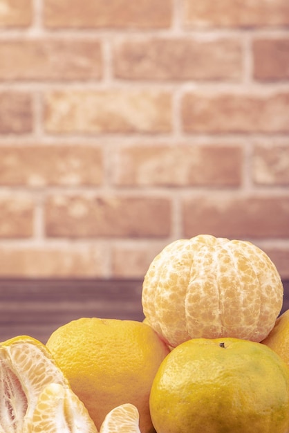 Photo peeled tangerines in a bamboo sieve basket on dark wooden table with red brick wall background chinese lunar new year fruit design concept close up