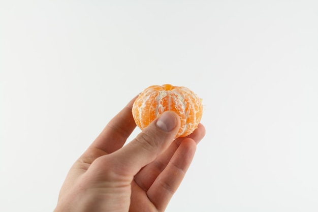 Peeled tangerines in hand on white background