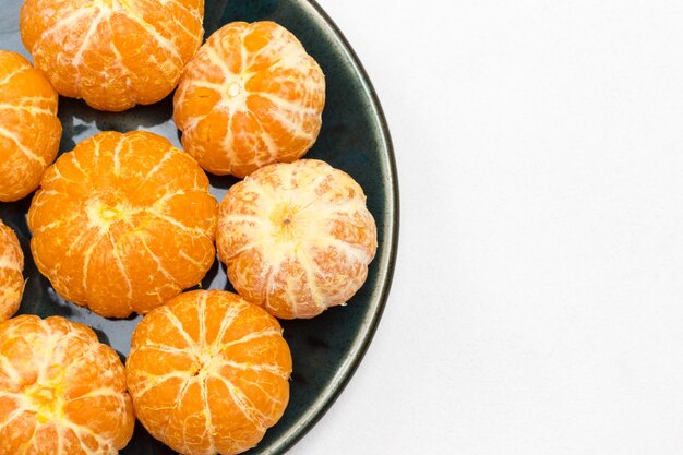 Photo peeled tangerines on plate. white background. flat lay. copy space