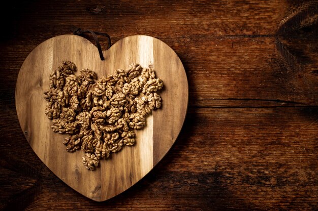 Peeled walnuts On a wooden board in the shape of a heart Healthy food Natural background Place for your text