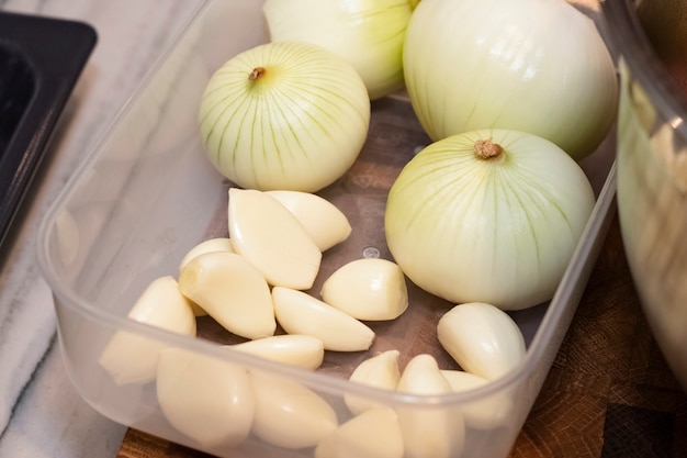 Peeled white onions and garlic in a plastic plate. Ingredients for cooking