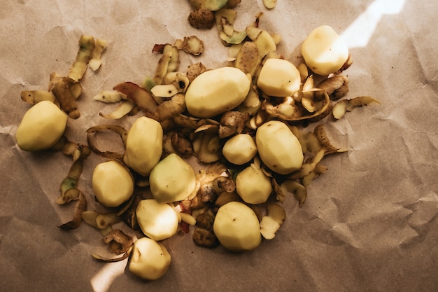 Peeled white potato with peel on paper