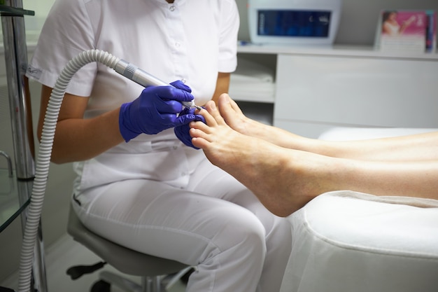 Peeling feet Pedicure SPA procedure in the beauty salon. Electric apparatus for pedicure. Woman getting her feet peeled in spa center