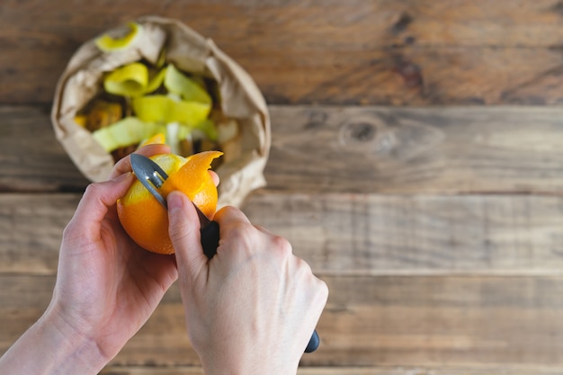 Photo peeling orange and bag of peels for compost.  rustic wood background.