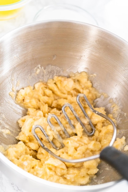 Peeling and smashing overripe bananas to make banana nut bread.