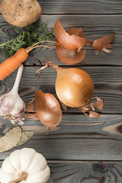 Peeling spicy white onion Flat lay view Fresh raw vegetables and flavorings Rinding onion on kitchen wooden table