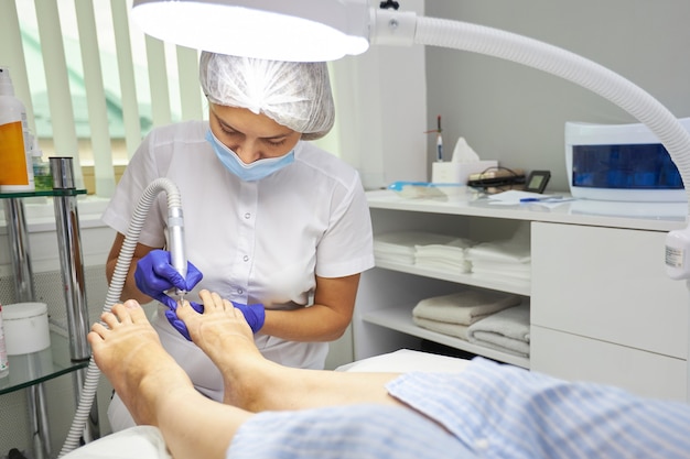 Peeling voeten Pedicure SPA procedure in de schoonheidssalon. Elektrisch apparaat voor pedicure. Vrouw laat haar voeten schillen in spacentrum