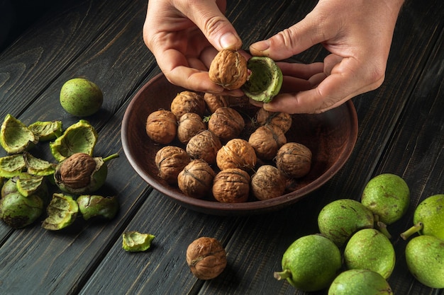 Peeling walnuts from green skins before preparing a culinary dish Closeup chef hands