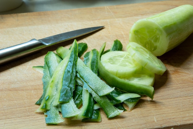 Peelings and sliced cucumber on a board