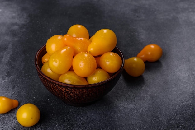 Peervormige kleine gele tomaten in een keramische plaat op een donkere betonnen tafel