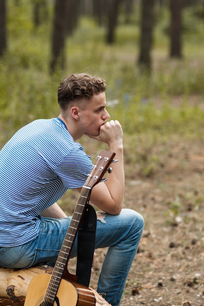 peinzend guitarissitting in bos op een boomschors. contemplatie