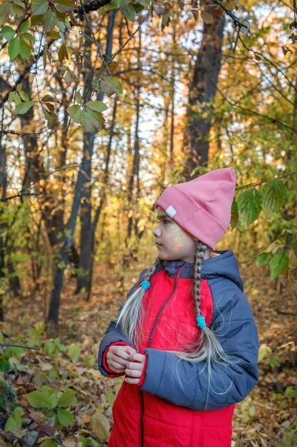 Peinzend preteen meisje dat alleen staat in een prachtig herfstbos tussen gouden bladeren