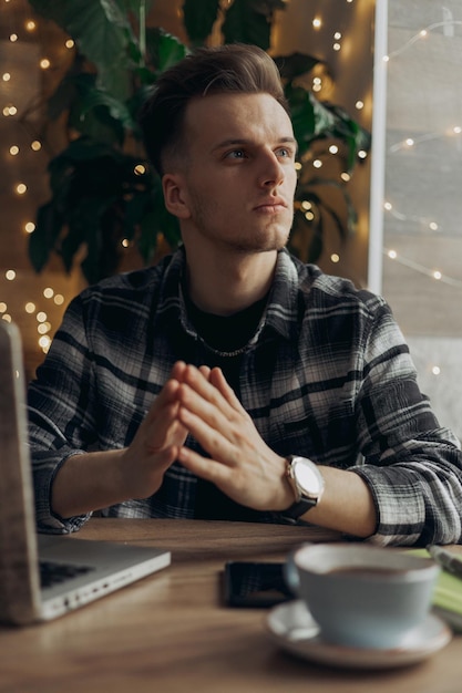 Peinzende jonge mannelijke ondernemer die nadenkt over een zakelijk project terwijl hij in een café werkt