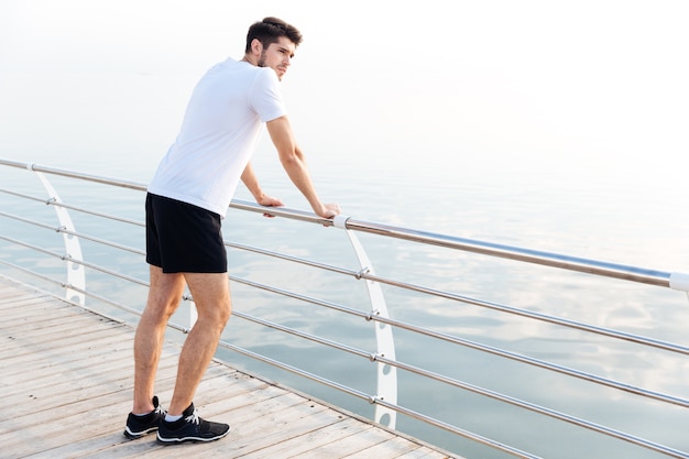 Peinzende jongeman atleet rust na het rennen op de pier