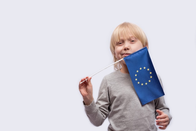 Peinzende jongen die de vlag van de Europese Unie houdt. Onderwijs in Europa.