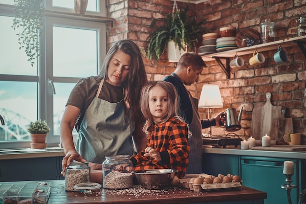 Peinzende moeder en haar dochtertje koken samen iets in de keuken.