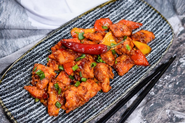 봄 양파와 토마토를 곁들인 북경 스타일 칠리 치킨은 중동 향신료의 음식 테이블 위에 분리된 접시에 제공됩니다.
