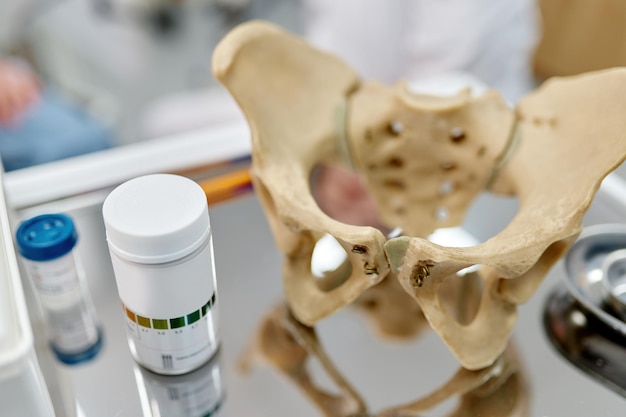 Foto modello di struttura scheletrica anatomica del bacino e pillole sul fuoco selettivo del tavolo. educazione medica e formazione presso l'ufficio del ginecologo