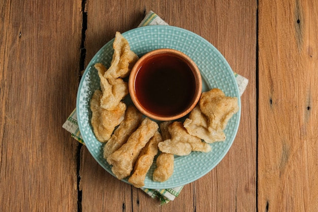 ペンペックは素朴な木製のテーブルでお召し上がりいただけます。ペンペックはインドネシアの伝統的な食べ物です。魚とタピオカでできており、甘くて特別なサワーソースまたはキュカと呼ばれる酢ソースが添えられています