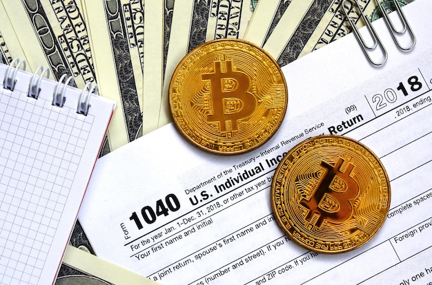 The pen, bitcoins and dollar bills is lies on the tax form 