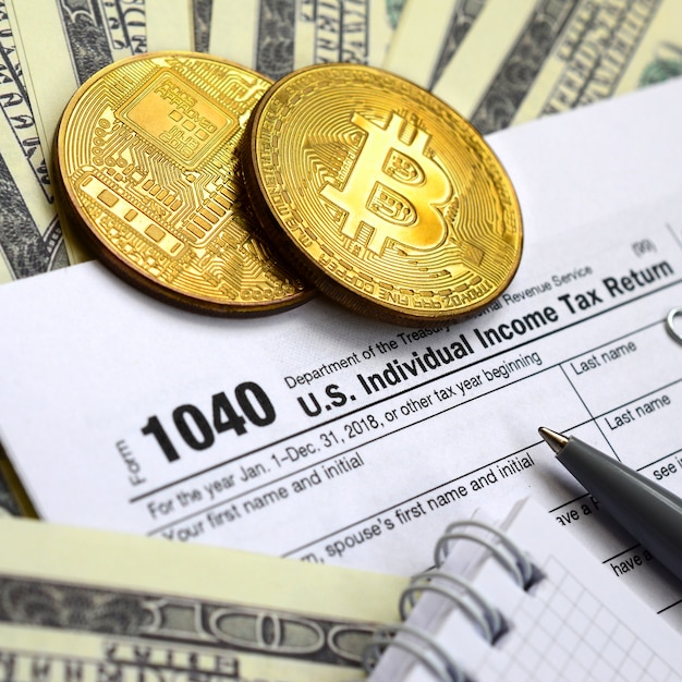 The pen, bitcoins and dollar bills is lies on the tax form 