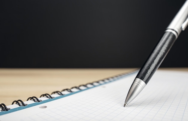 Photo pen on blank notebook on table and black background with copy space writing or signing concept