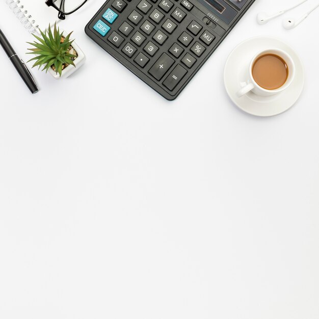 Pen,cactus plant,calculator,earphones and coffee cup on white background