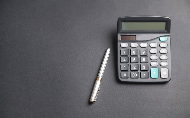 Pen and calculator on the black background.