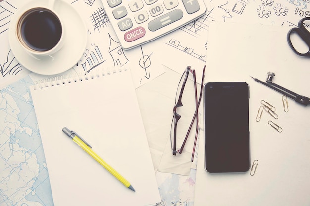 Photo pen, calculator, phone, coffee and glasses on table