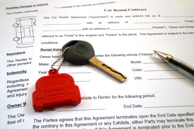 Pen and a car key on the top of an car rental contract form