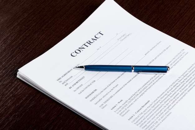 Photo pen and contract papers on wooden desk