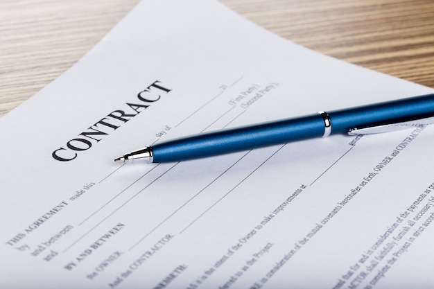 Photo pen and contract papers on wooden desk