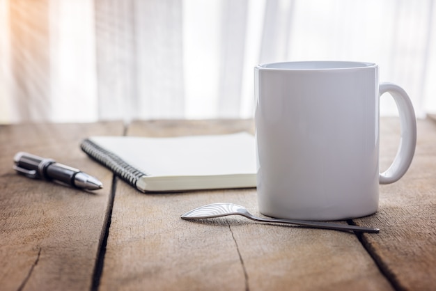 Pen en notitieboekje met koffiekop op houten