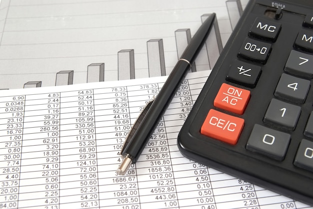 Pen en rekenmachine op papieren tafel met financiële diagram