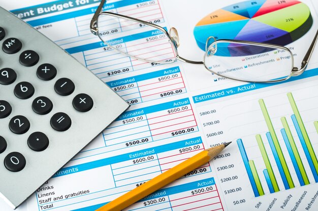 Ручка, очки и калькулятор на бизнес-графиках и диаграммах