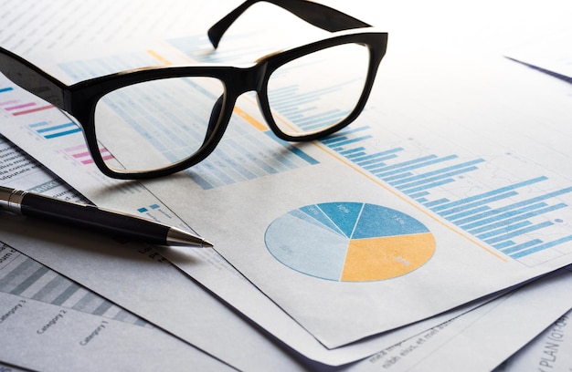 Pen and glasses on financial graph chart.For business concept.