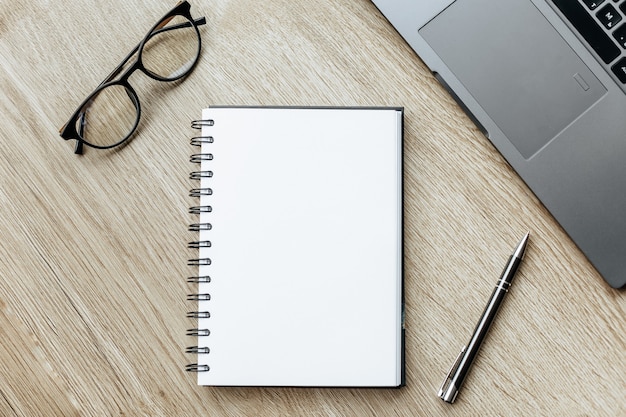 Pen, glasses and Notepad on the wooden desk Business concept