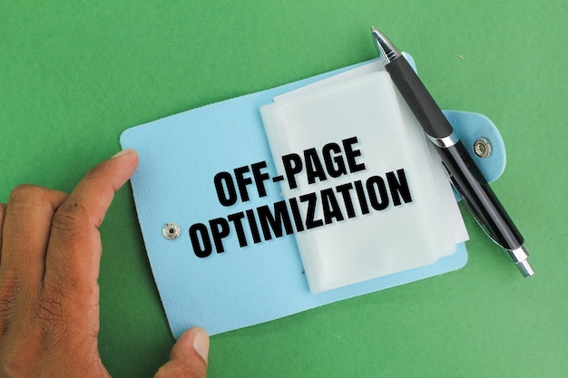 pen and hand holding a book with the word OFFPAGE OPTIMIZATION Seo concept