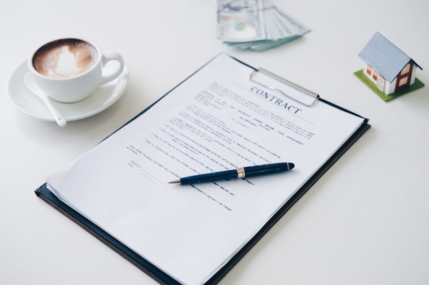 Photo pen on house insurance document and contract document near coffee cup