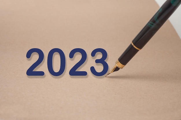 2023이라는 단어가 적힌 종이 위에 펜이 놓여 있습니다.