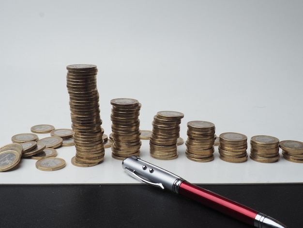 Photo a pen is next to a stack of coins with a pen on top of it.