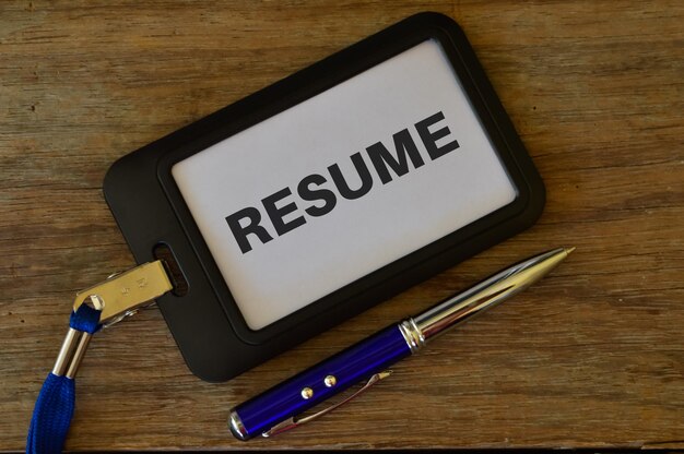 Photo pen and name tag written with resume over wooden background